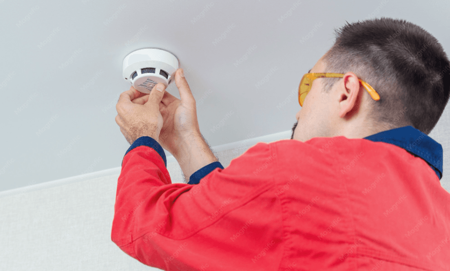 Electrician testing a smoke alarm on a ceiling